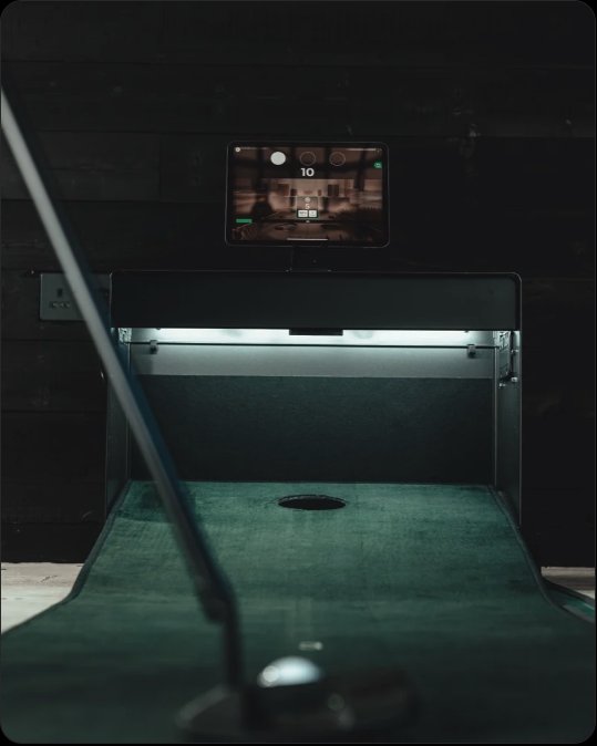 The PuttR simulator set up indoors, showing the putting surface, hole and overhead display